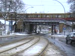 Eine Straenbahn mit Vollwerbung www.gelbeseiten.de auf der Linie M17 in Berlin Karlshorst. Im Hintergrund zu sehen eine ausfahrende S-Bahn der Linie S3. Strae (Treskowallee) und Bahnunterfhrung sollen in den nchsten Jahren umgebaut werden. 1.1.2010