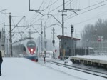 Ein  Сапсан  (Sapsan) Velaro EWS1 fährt durch den verschneiten Bahnhof von Kolpino in Richtung Sankt Petersburg, 18.2.18