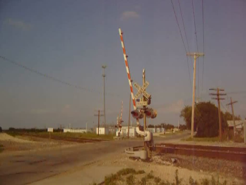 Bahnbergang mit herannahendem BNSF Gterzug (Dash-9 Lokomotive)in Rose Hill, Kansas im April 2006