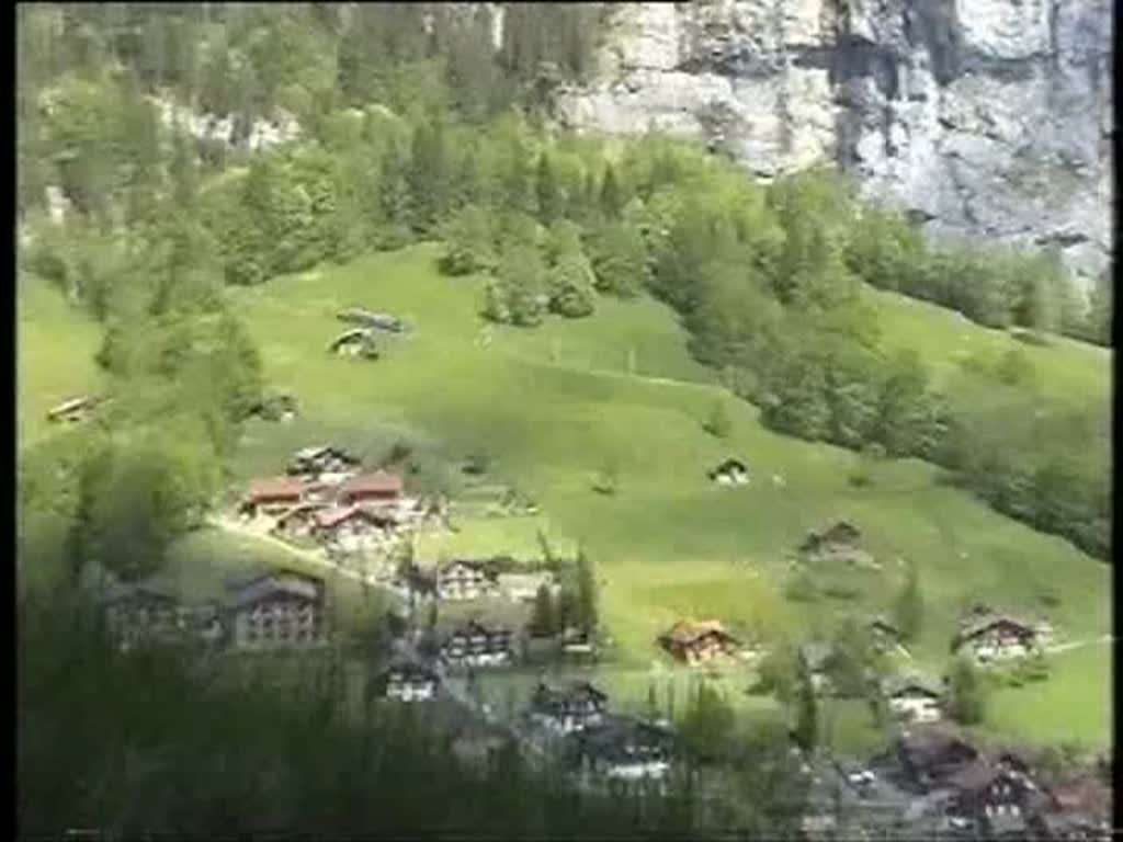 Berner Oberland 2004 (VHS-Archiv) - Oberalb von Lauterbrunnen knnen wir an der gegenberliegenden Bergseite die Zge der Wengernalpbahn beobachten. Zei Gterzge sind talwrts unterwegs. Das rauschen kommt von einem Bergbach direkt neben uns. 24.05.2004.