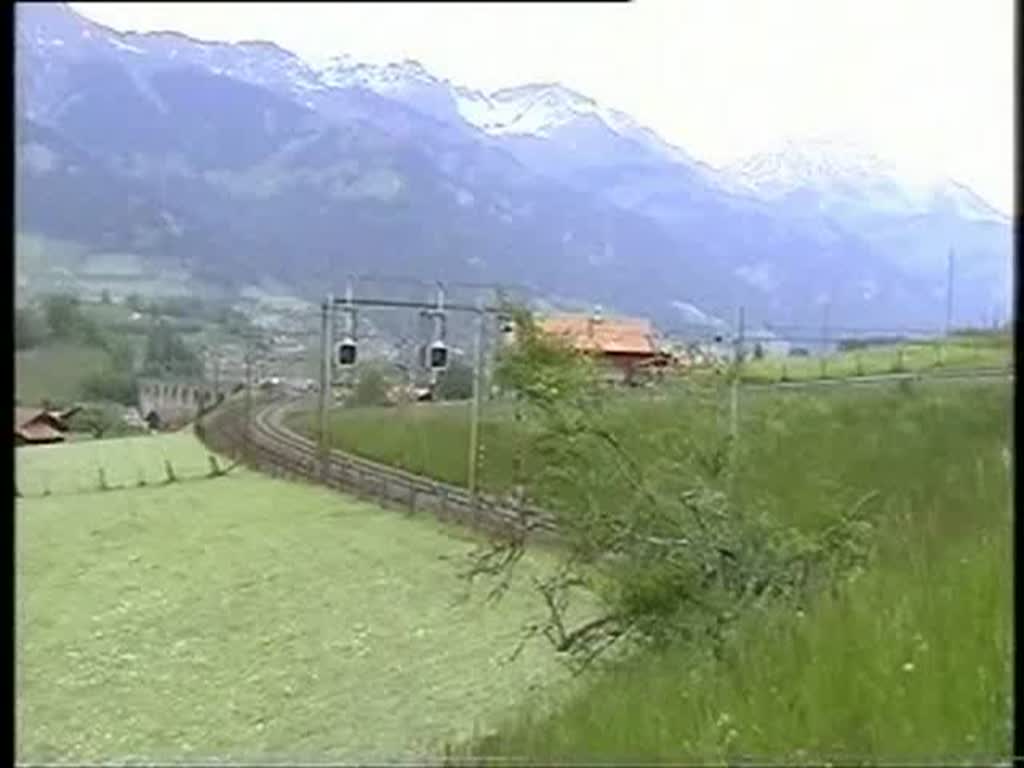 Berner Oberland 2004 (VHS-Archiv) - Mit einem InterCity rollt am 26.05.2004 die Re 460 038-3  Hauenstein  am Ltschberg talwrts - auf dem falschen Gleis. Grund ist die ihr folgende  Rollende Landstrae , die mit einer recht seltenen Traktion aus Re 465 und Re 4/4 auf dem Regelgleis ebenfalls talwrts unterwegs ist, leider an nicht sehr fotogener Stelle. 