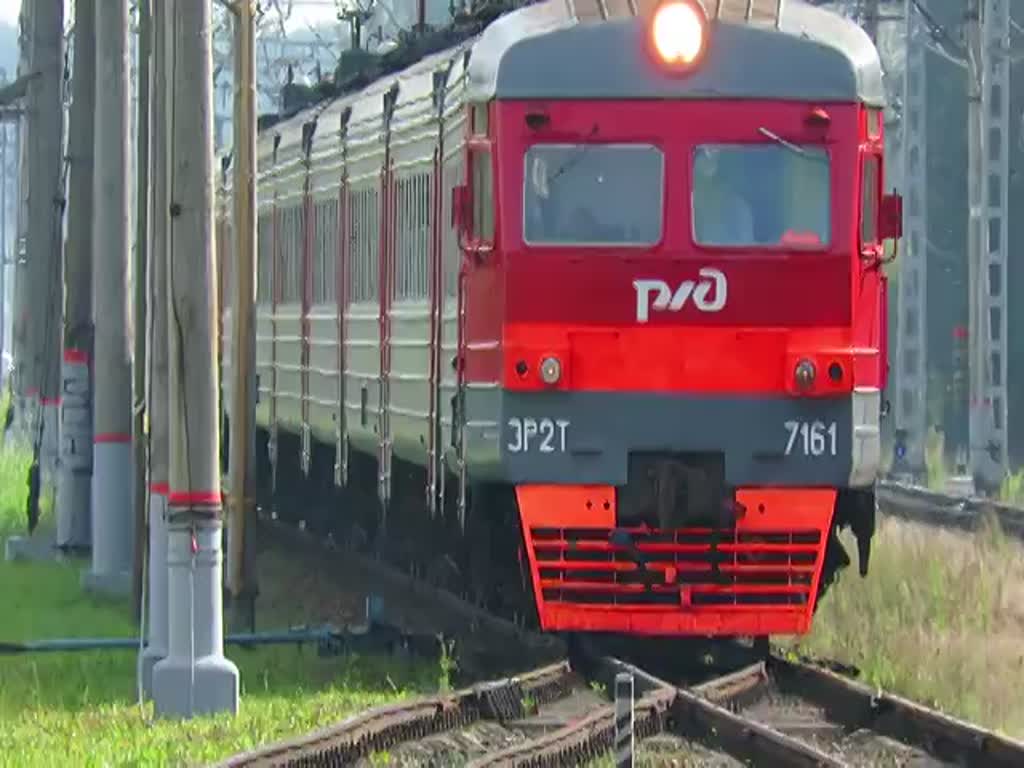 Einfahrt von ЭР2T (ER2T) 7161 auf Gleis 3 in den Bahnhof Царское Село (Zarskoje Selo), bei St. Petersburg, 19.8.17, über den Bahnübergang, wo geschlossene Schranken für Fußgänger offenbar nicht gelten, das Pfeifen des Zuges nur  schneller gehen  bedeutet, und erst wenn der Zug hupt wird es wirklich ernst :-)