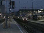 Eine Alex-Garnitur mit Kurswagen nach Lindau und Oberstdorf wird von einer Lok der Baureihe 223 aus dem Münchener Hbf gezogen und verschwindet in der Abenddämmerung im riesigen Gleisvorfeld.