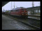 Einfahrt eines Doppelstockzuges mit roten und blauen (mintgrnen)  Wagen, gezogen von einer Lok der BR 111.