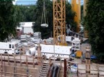 Neubaustrecke U5 der Berliner U-Bahn. Kurz bevor die Tunnelbohrmaschine im Berliner Untergrund verschwindet hier ein paar bewegte Bilder von der Zuführung der Tübbings (Beton Tunnelteile). Die gerade benötigten Tübbings lagern auf dem Baustellengelände und werden mit Hilfe von Kränen in den Startschacht der Tunnelbohrmaschine gehoben. Dort werden die Betonteile auf ein gleisgebundenes Gefährt gelagert und unter der Tunnelbohrmaschine hindurch dem Kopf der Maschine zugeführt. Direkt hinter dem Schneidrad werden die angelieferten Tübbings dann sofort von der Bohrmaschine erfasst und Segment für Segment zu einem runden Tunnelteil zusammengesetzt. Der Abraum aus dem Tunnel wird über Rohrleitungen einer Entwässerung zugeführt und anschließend durch einen Schaufellader zu einer im Bauhafen liegenden Frachtschute gebracht. Viele Lastwagenfahrten durch das Berliner Stadtgebiet werden dadurch gespart. Film:12.07.2013  